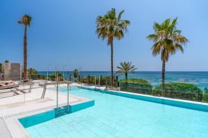 马贝拉El Fuerte Marbella的一座棕榈树和海洋游泳池