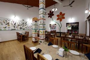 坎哈Tathastu Kanha的一间带桌椅的用餐室和一个大壁画