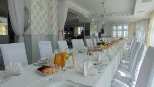 什切青巴慈科酒店的一张长白桌子,上面有白色的椅子和盘子
