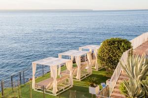 伊利塔斯Hotel ROC Illetas & SPA的一排白色的桌椅,俯瞰着水面