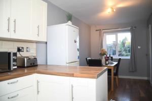 Willenhall2ndHomeStays- Willenhall-A Serene 3 Bed House with a Garden View-Suitable for Contractors and Families-Sleeps 9 - 7 mins to J10 M6 and 21 mins to Birmingham的厨房配有白色橱柜和木制台面