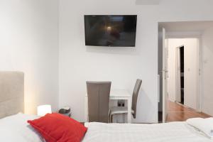维也纳Modern 1BR Apart- Suitable for Longstays的一间卧室配有一张床和一张桌子,墙上配有电视