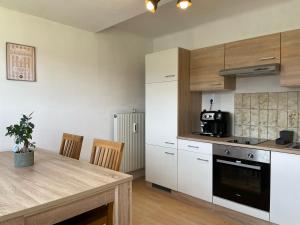 塞博登Maxi'Seeblick Apartments的厨房配有白色橱柜和木桌