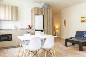 赫雷斯-德拉弗龙特拉Top & Chic Albarizuela Suites - Apartamentos Jerez的厨房以及带白色桌椅的起居室。