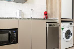 赫雷斯-德拉弗龙特拉Top & Chic Albarizuela Suites - Apartamentos Jerez的厨房配有微波炉、洗衣机和烘干机