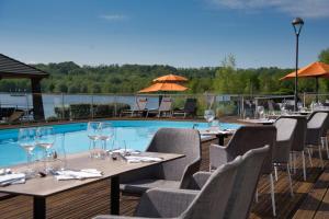 沙穆伊Hôtel du Golf de l'Ailette, The Originals Relais (Qualys-Hotel)的游泳池旁的一排桌椅