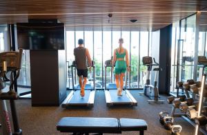 阿德莱德Vibe Hotel Adelaide的男人和女人在健身房里跑步