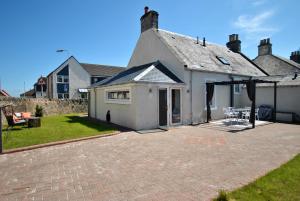 安斯特拉瑟Shore Cottage Anstruther- stylish home by the sea的庭院内带庭院的白色房屋