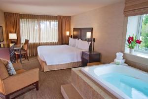 贝尔维尤Eastgate Hotel - BW Signature Collection的酒店客房设有一张大床和一个浴缸。