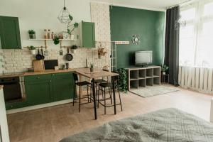 ĶegumsStudio type apartment in Ķegums的厨房配有绿色橱柜和带凳子的桌子