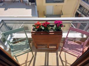 海若克利欧365 Urban Suite的阳台上配有两把椅子和一张带鲜花的桌子
