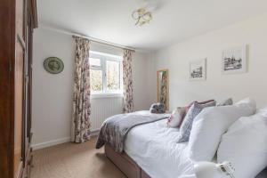 切尔滕纳姆Luxury Cheltenham Home with EV charger - Lechampton Hills的一间卧室配有一张带白色床单的床和一扇窗户。
