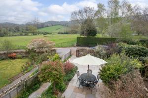切尔滕纳姆Luxury Cheltenham Home with EV charger - Lechampton Hills的花园内桌椅和遮阳伞