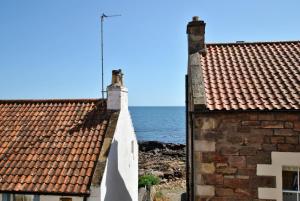 安斯特拉瑟Heron Cottage- fishermans cottage by the sea的两座以海洋为背景的建筑的屋顶