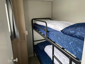 比丁赫伊曾Houseboot Cormorant, lake view的一间卧室配有两张双层床,铺有蓝色和白色的床单