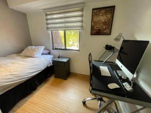 圣地亚哥Departamento Delux的一间卧室配有一张桌子、一台电脑和一张床