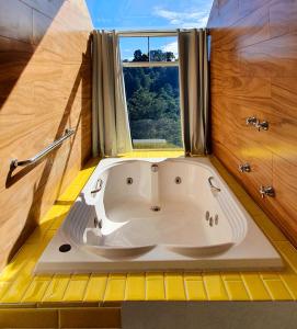 坎波斯杜若尔当金色森林普萨达酒店的带窗户的浴室内的白色浴缸