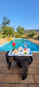 瓦尔任博尼塔Pousada Chales da Canastra的一张桌子,上面有食物,放在游泳池边