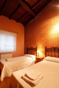 坎德拉里奥Casa Rural Puerta del Sol de 3 habitaciones的一间卧室设有两张床和砖墙
