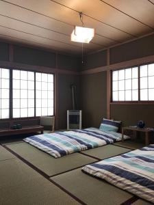 小樽Garden House Umenoya Otaru的带三扇窗户的客房内的两张床
