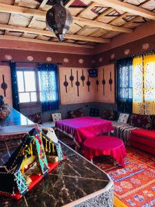 凯拉Kasbah Tialouite的一间设有粉红色桌子、沙发和窗户的客房