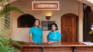 格拉纳达Boutique Hotel Secret Garden Granada的两个身穿蓝色衬衫的女人站在柜台前