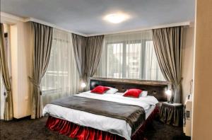 希萨里亚Astrea Deluxe的酒店客房配有一张带红色枕头的大床