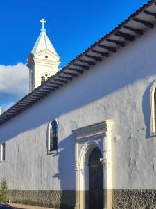 昆卡Hotel Casa Merced的一座白色的教堂,有陡峭的陡峭的陡峭壁和一扇门