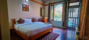 本贾尔Tirthan Grand Riverside的一间卧室设有一张床和两个大窗户