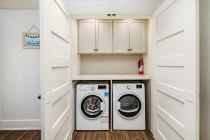 温哥华Gorgeous 4-Bedroom Garden Level Suite at Vancouver West的洗衣房配有白色橱柜、洗衣机和烘干机