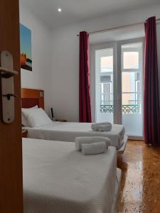 里斯本House Rooms in Bairro Alto的酒店客房设有三张床和窗户。