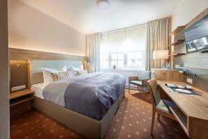 阿滕多恩Struck Landhotel & SPA的酒店客房设有一张大床、一张书桌和一张书桌。