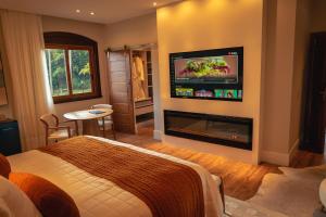 伊泰帕瓦Saison Resort & Spa的一间卧室设有一张床和一个壁炉,配有电视