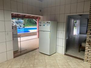 若阿诺波利斯Pousada camping Recanto Joanópolis的厨房配有白色冰箱和窗户。