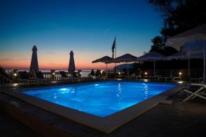 阿齐欧斯·贡多斯Kostas Beach Apartments的夜间游泳池,配有椅子和遮阳伞