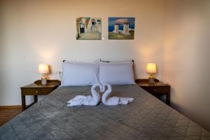 古瓦伊Mayia Sunset sea front house Gouves Heraklion的床上的两条天鹅毛巾和两盏灯
