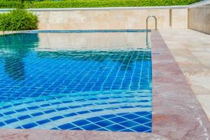 玛诺Holiday Inn Express & Suites - Austin - Manor, an IHG Hotel的铺有蓝色瓷砖的游泳池和游泳池