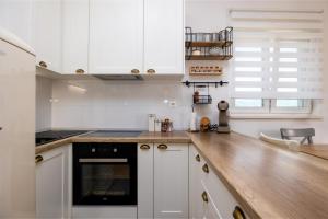 斯普利特Apartment Ivy的厨房配有白色橱柜和木制台面