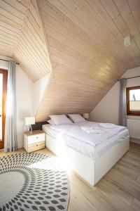 IdzbarkUroczysko Lubajny的一间卧室设有一张带木制天花板的大床