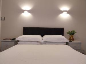 兰迪德诺The Rosedene的卧室配有一张带两个灯的大白色床