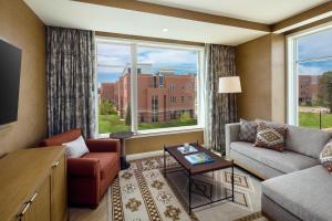 奥罗拉The Benson Hotel & Faculty Club的带沙发和椅子的客厅以及大窗户。