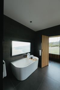 潘尼萧CABN Kangaroo Island的黑色浴室设有大型白色浴缸,设有窗户