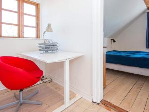 格雷诺Holiday home Grenaa XLVIII的一张红色椅子,位于带桌子和床的房间