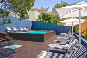 波尔图Casa da Marechal - Boutique Hotel by Oporto Collection - Adults Only的蓝色墙壁旁的游泳池,配有椅子和遮阳伞