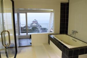 热海Mujuan的带浴缸的浴室和美景窗户。