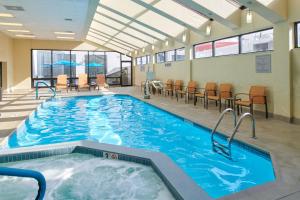哥伦布哥伦布市区万怡酒店的一个带椅子和桌子的大型室内游泳池