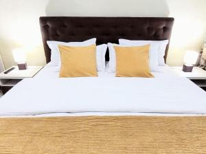 雅西Simona Apartament Palas Mall 1的一张配有白色床单和黄色枕头的大床