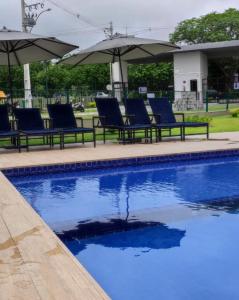 卡鲁阿鲁Studio Garden 01 Quartos的一个带蓝色椅子和遮阳伞的游泳池