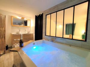 维希Maison de ville, SPA Balnéo, 2 suites parentales的浴室配有大浴缸及水槽