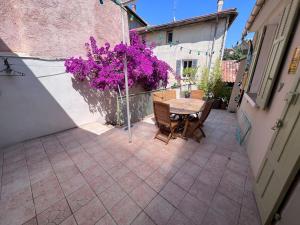 耶尔Maison dans les rues piétonnes du vieux Hyères的一个带桌子和紫色鲜花的小庭院